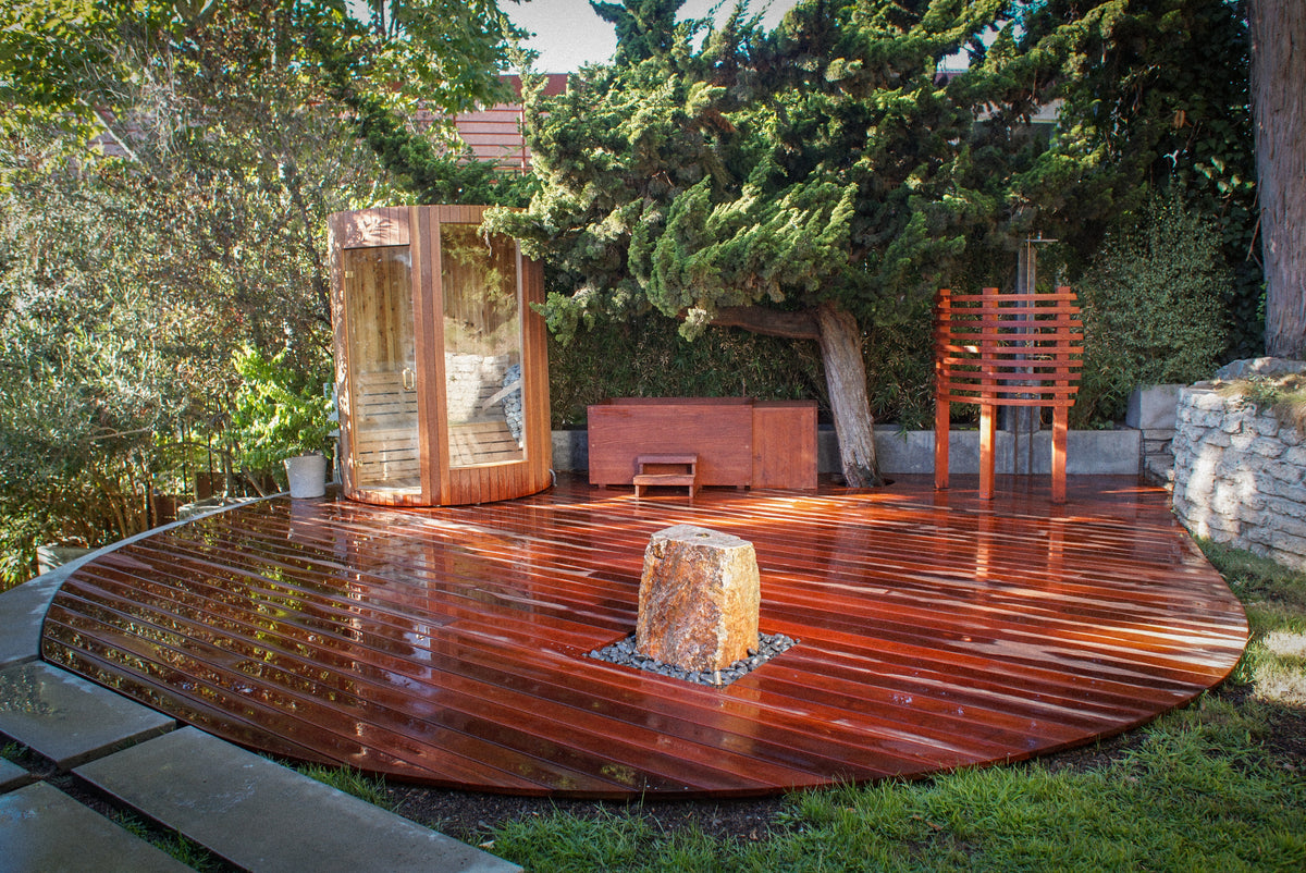 A Tubpanga-built circular redwood bathing deck with sauna and outdoor shower, glistening after use, surrounded by garden.